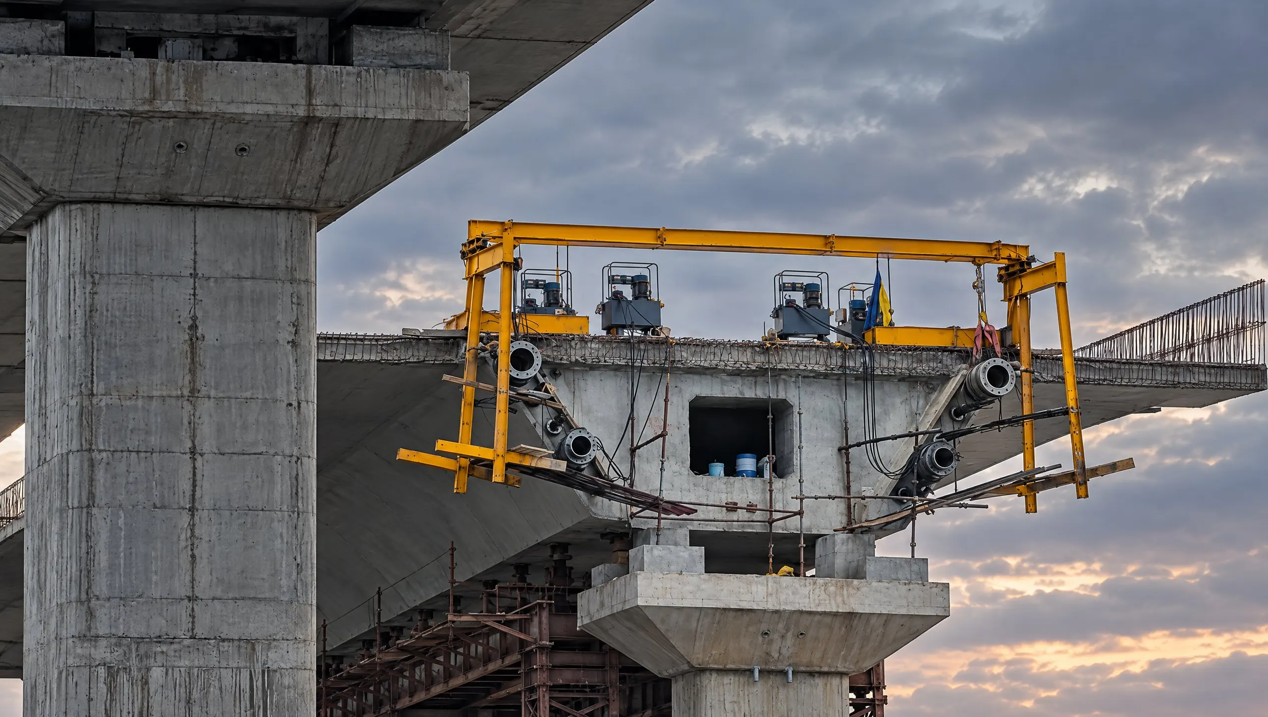 A post-tensioned girder during stressing: TYROS anchorages on the girder end face, hydraulic jacks on the yellow gantry above
